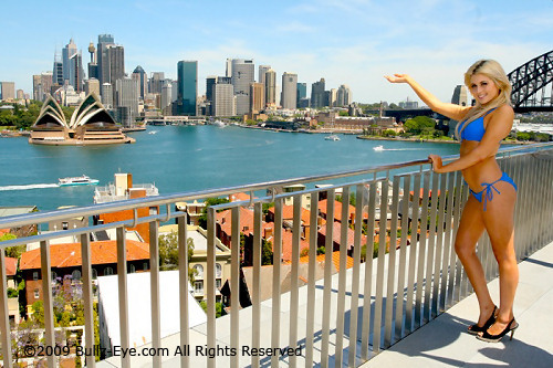 Cassie in blue bikini overlooking Sydney harbor with view of Sydney Opera House