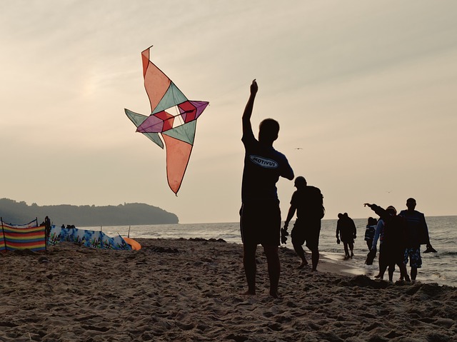 boy flying a kite with family on the beach