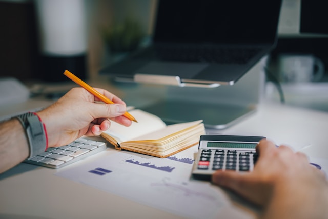man's hands on desk with notepad and calculator