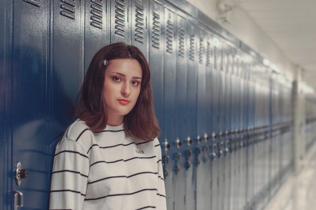 teenager in school hallway next to lockers