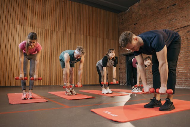 people in workout group with dumbells and matts