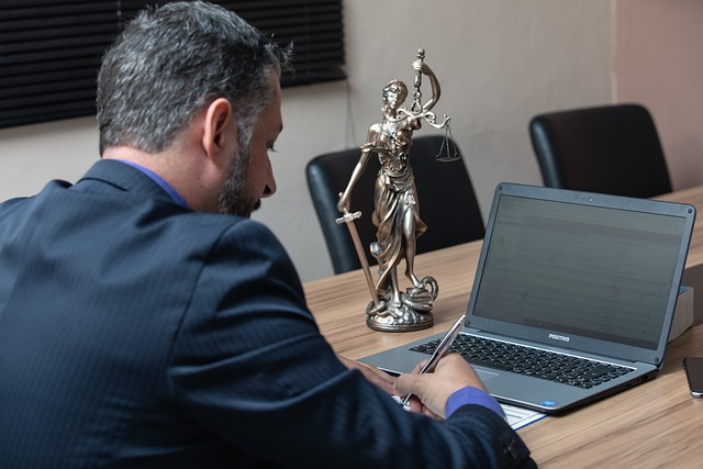 man working at desk with laptop rear angle view