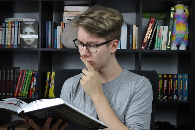 male student in glasses reading book