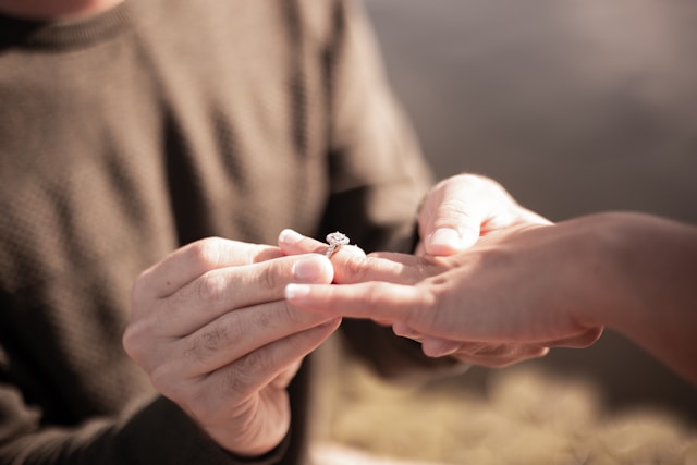 close-up of man putting engagement ring on woman's finger