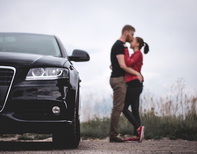 couple kissing on road next to their car
