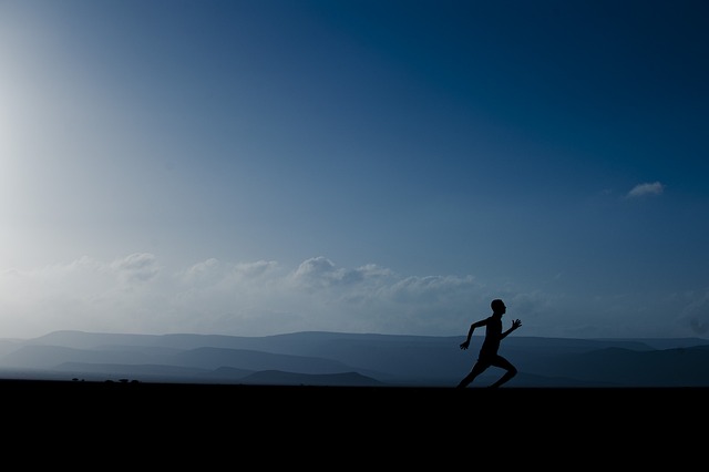 man running at dusk with landscape behind him
