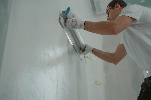 man fixing a wall inside a home