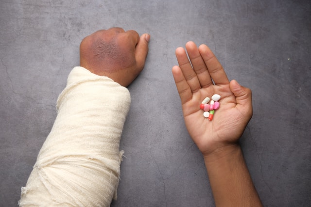 person's hands with right hand holing pills and left hand with bandage