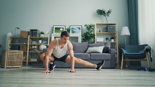 man in white tank top and black shorts and sneakers doing stretching in living room