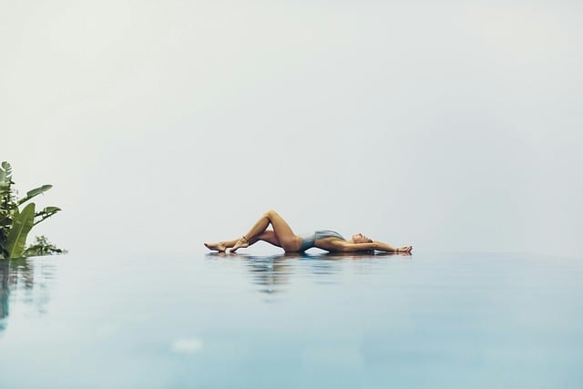 woman in swimsuit laying on her back at edge of infinity pool
