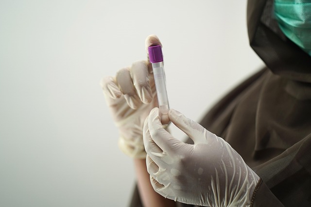 person with gloves holding blood test sample in tube