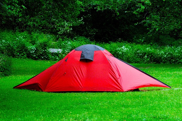 red camping tent resting on grassy field