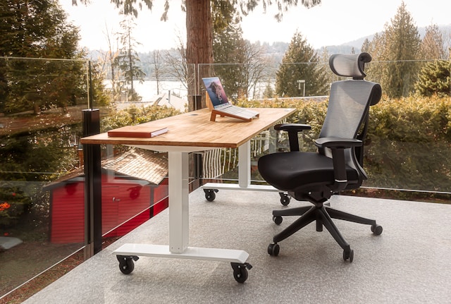 desk with laptop on it and chair on a patio with a view