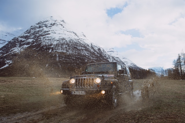 Jeep on road in cold weather near white capped mountain