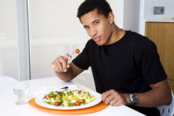 black man in black t-shirt eating meal at table