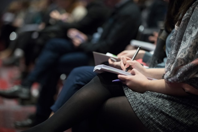 closeup of people in audience taking notes