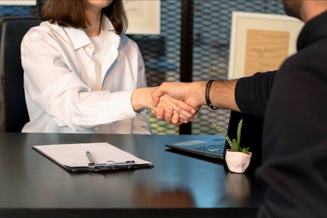 closeup of wman and man shaking hands over a table while sitting down