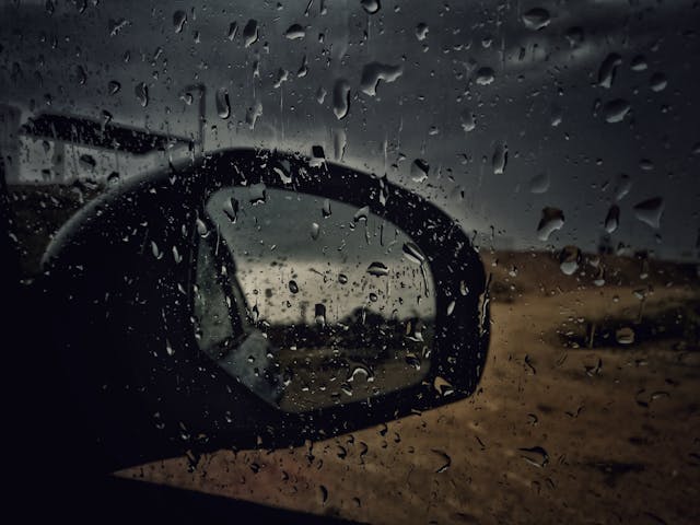 side mirror on car with water droplets seen through side car window