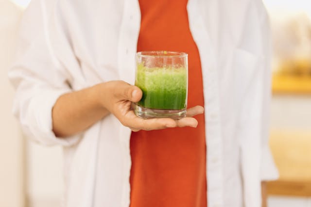 green smoothie in glass held in hand