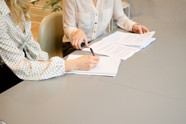 closeup of two women working on papers on table
