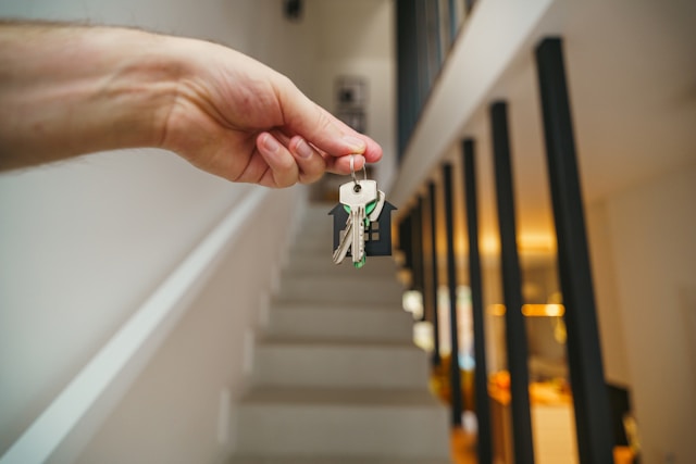 closeup of hand holding keys with stairs in background