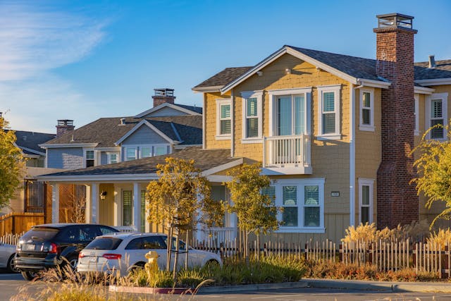 yellow house with white trim with two cars parked in front