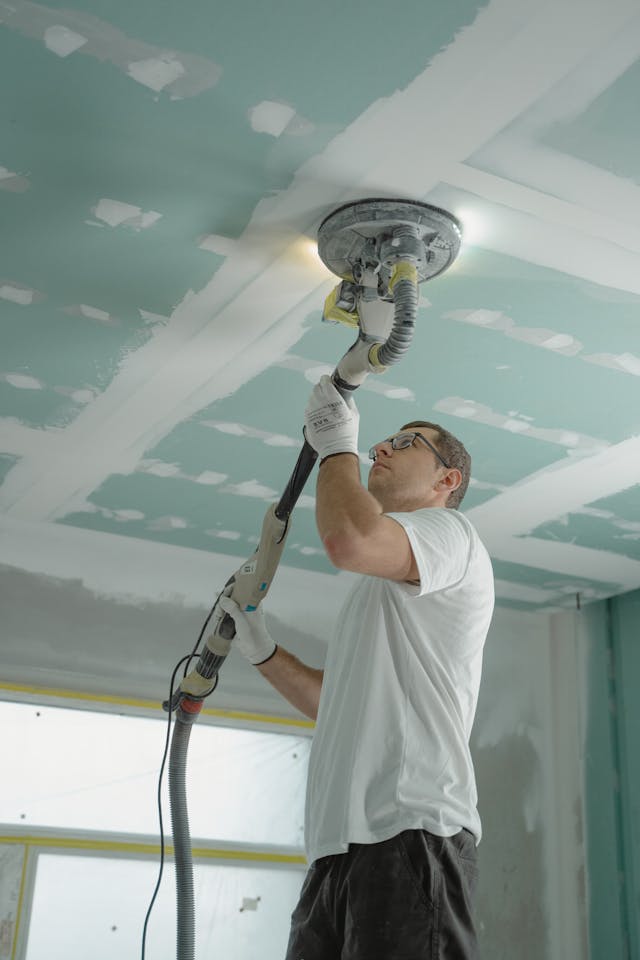 man in white shirt sanding a ceiling