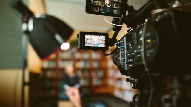 camera filming woman sitting in front of bookshelf