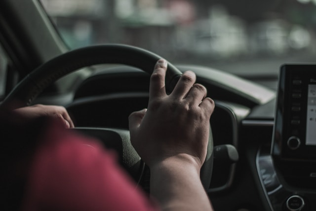 person's hand on car steering wheel