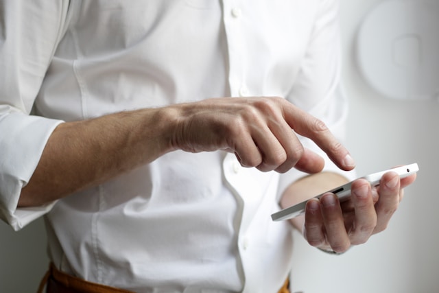 close-upof hand of man in white shirt holding smartphone