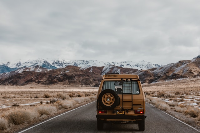 rear view of SUV traveling on road with mountains in background
