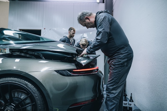 man working on damaged car in garage