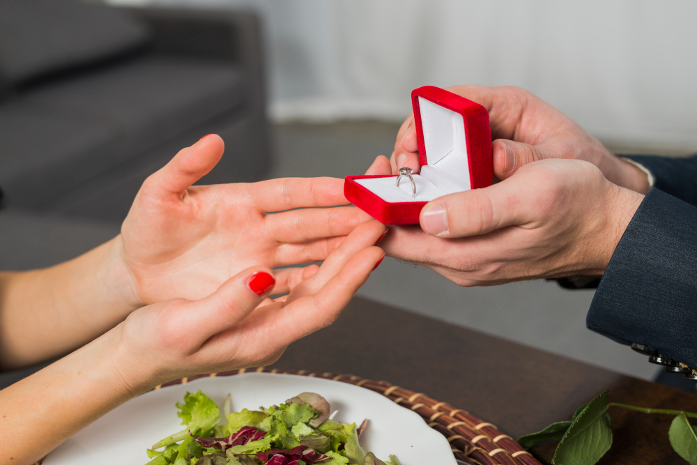 close-up of man giving woman engagement ring in red box
