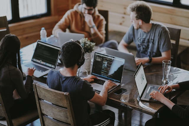workers with laptop around table in office