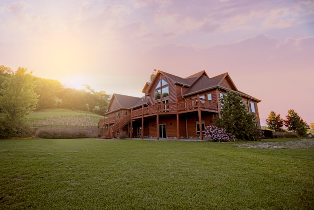 brown wooden house with large grass field