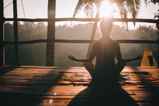 rear silhouette view of woman doing yoga at sunrise