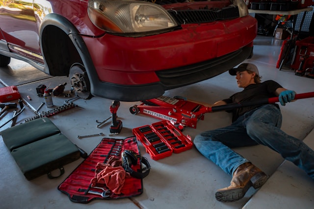man laying on ground working on red car in garage