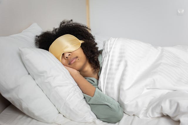 pretty black woman sleeping on bed with yellow blinder and white blanket