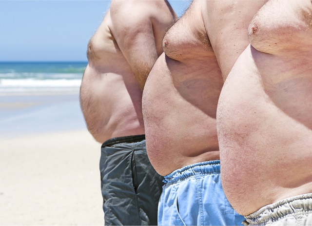 three shirtless men with bellies on the beach