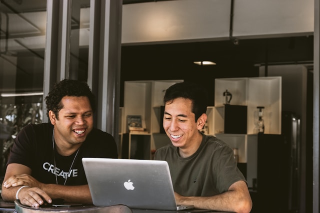two men working at desk with laptop