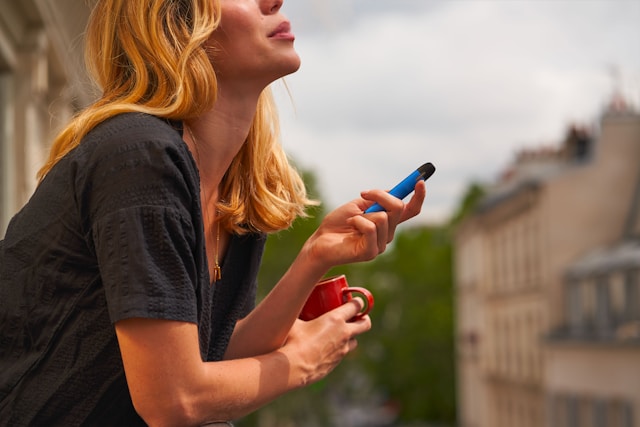 blonde woman holding red cup and cell phome