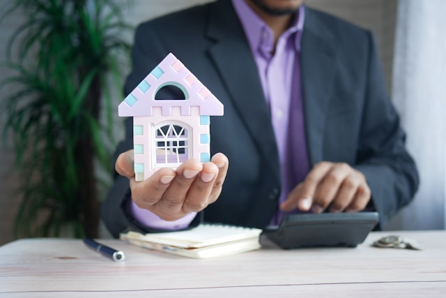 man in suit holding toy house