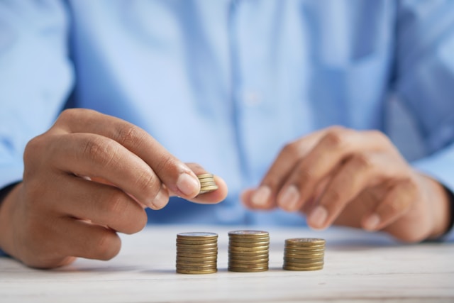 closeup of man's hands stacking coins on table