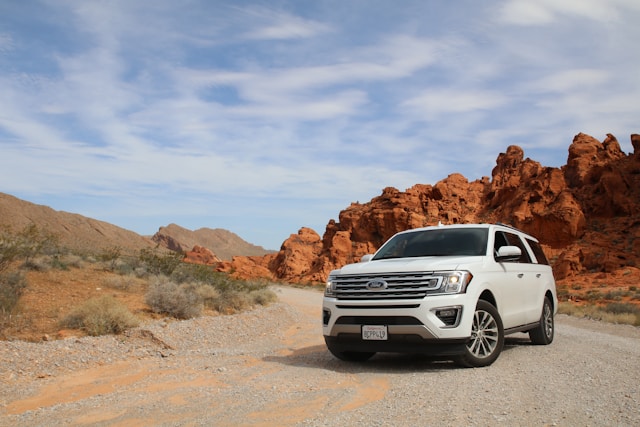 white Ford SUV on dirt road