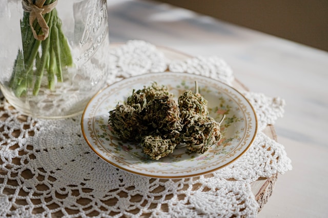 Dried cannabis flower buds stored in a clear glass jar resting on a wooden table