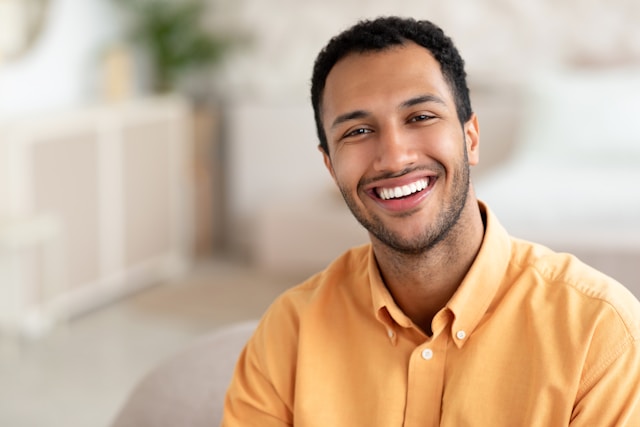 man in tellow shirt smiling with nice white teeth