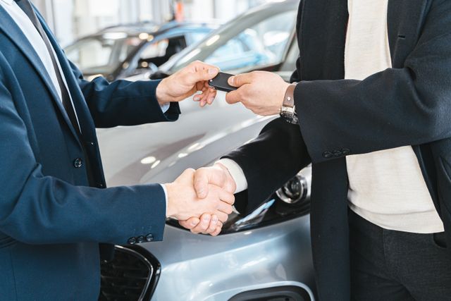 handing over car keys and shaking hands