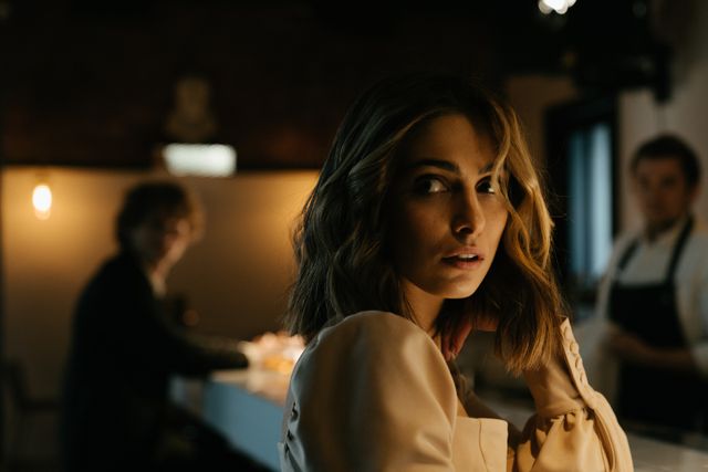 pretty woman with brown hair at bar with man in background