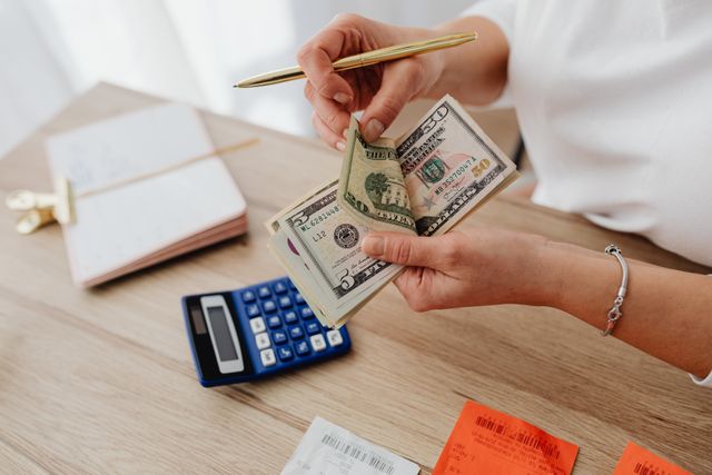 close-up of woman's hands holding money over desk