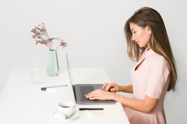 pretty brunette woman sitting at desk on laptop
